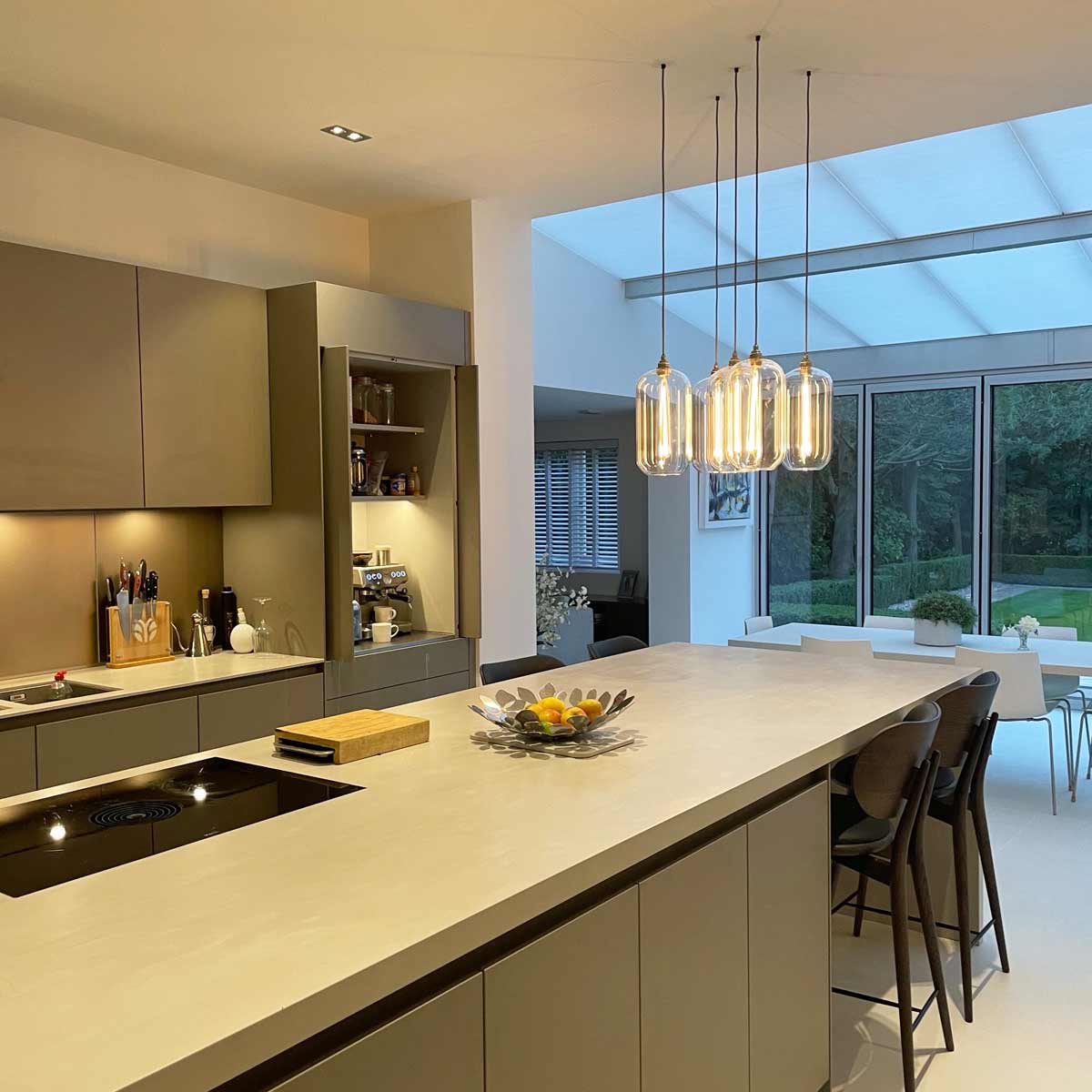 South Charlotte Fine Lighting sell glass pendant lights kitchen, seen here in a cluster above a kitchen island. This particular model is the Charlton Pendant Light in size Medium.