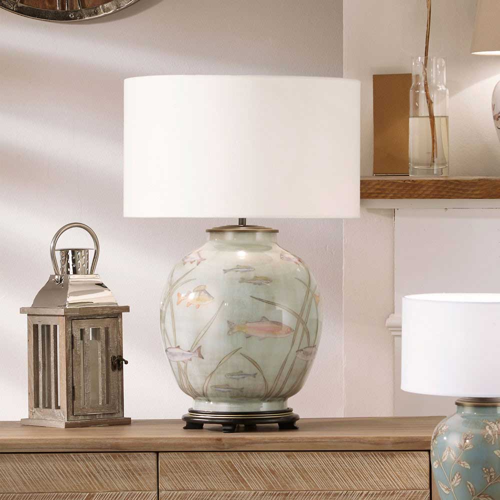 The Fish Large Glass Table Lamp by Jenny Worrall is shown here with a cylinder lampshade, both of wihich are sold by South Charlotte Fine Lighting