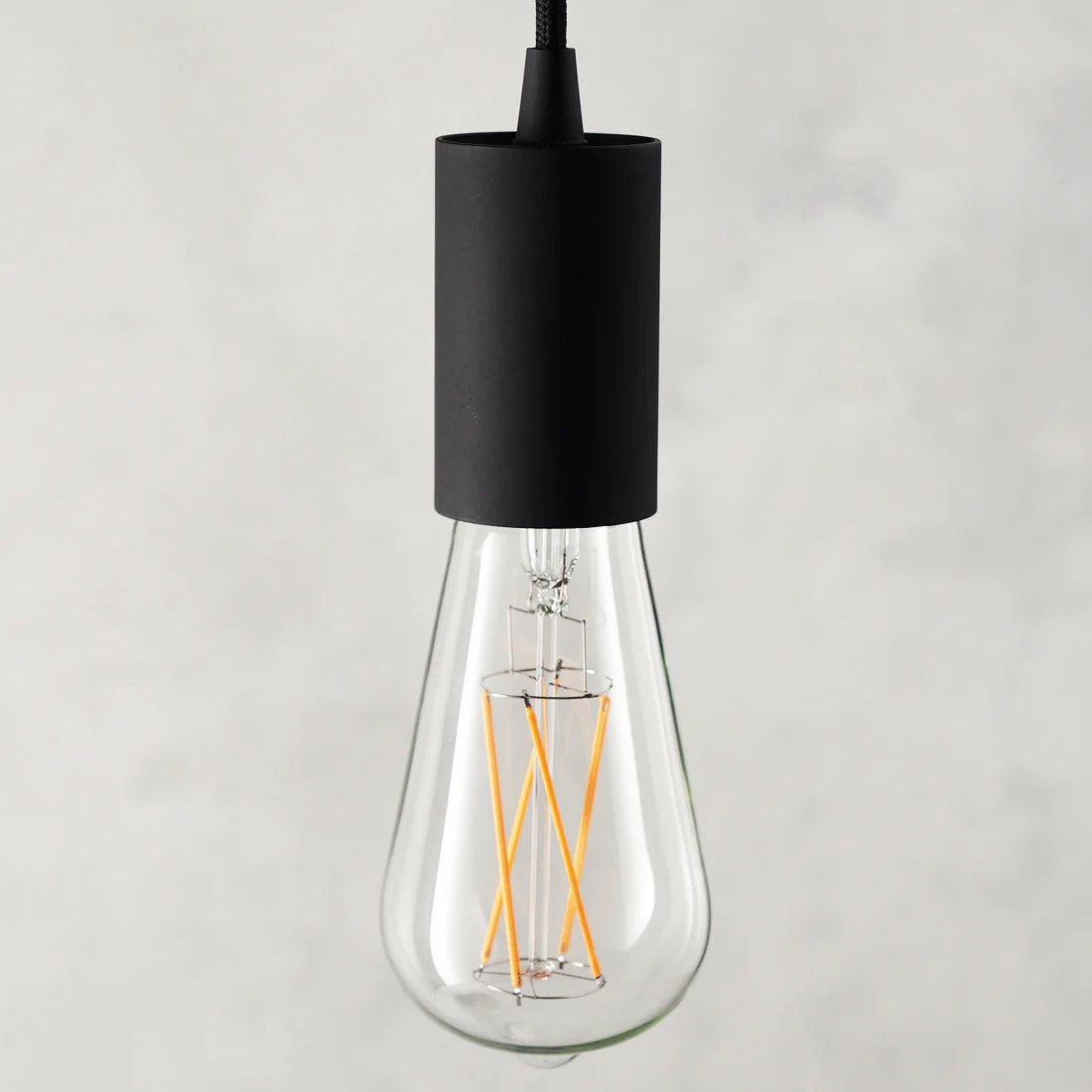 The Well Lit Leo LED light bulb is pictured with a Well Lit Spin Pendant Light in Black and sold by South Charlotte Fine Lighting