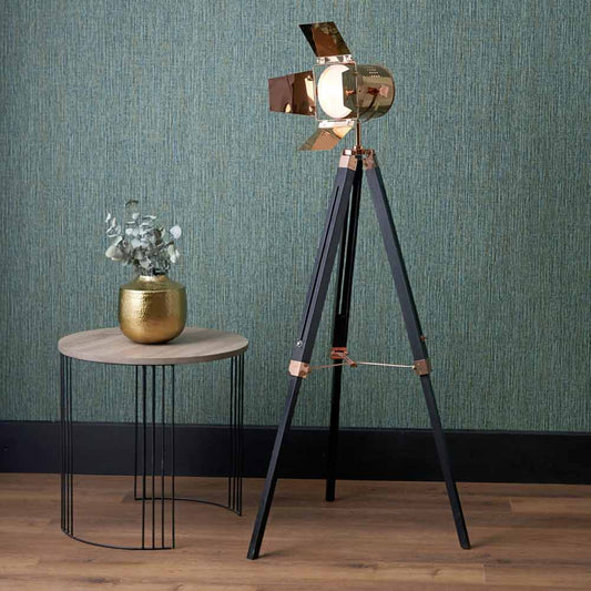 Copper tripod floor lamp with a black wooden base.