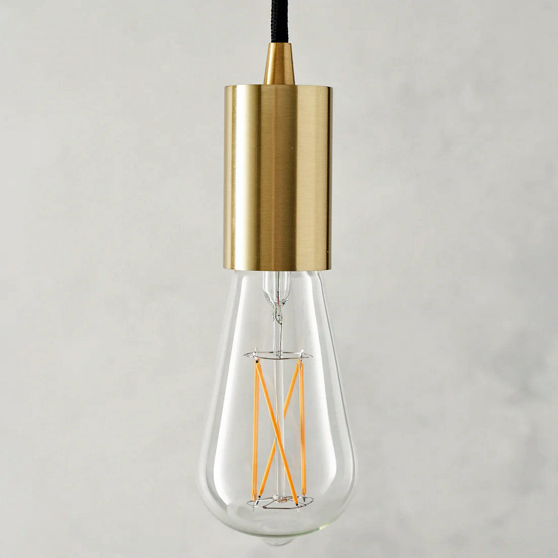 The Well Lit Leo classic LED light bulb is pictured with a Well Lit Spin Pendant Light in Brass and sold by South Charlotte Fine Lighting